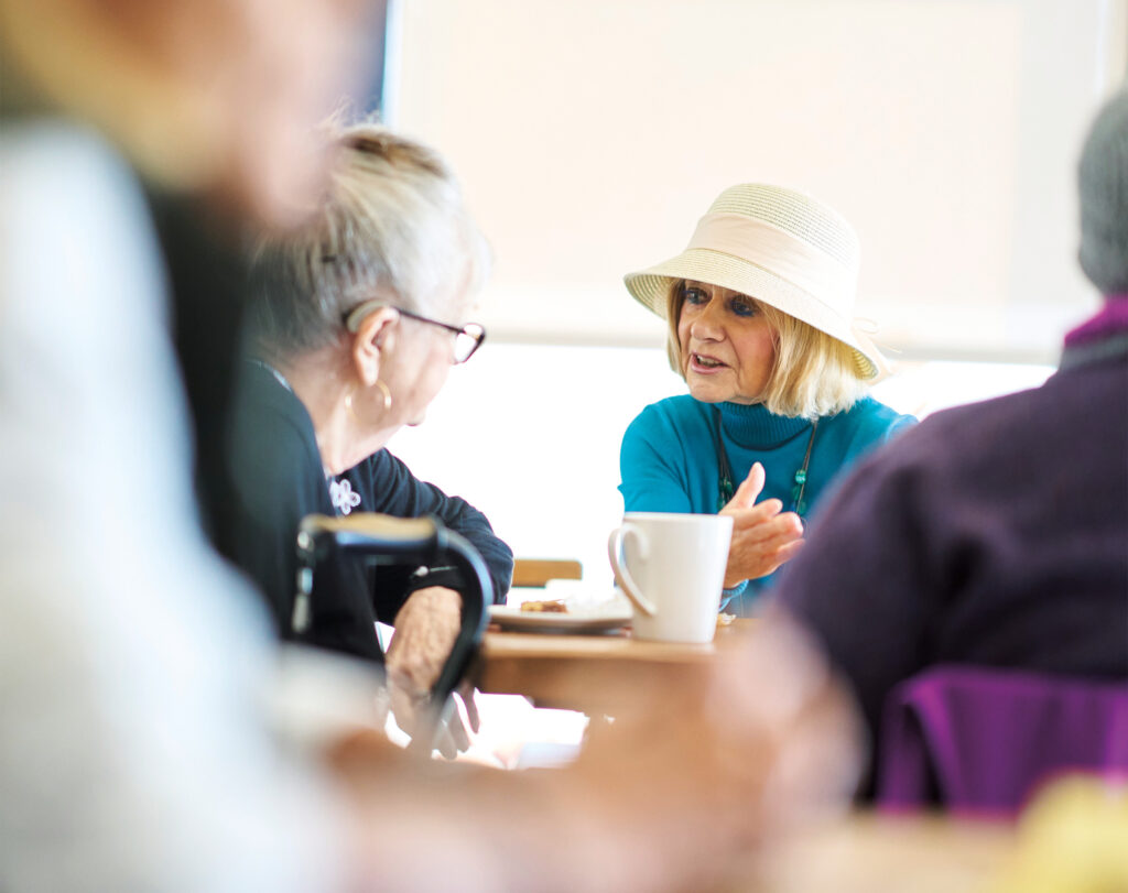 Photo of Shirley Little at a coffee shop talking to people